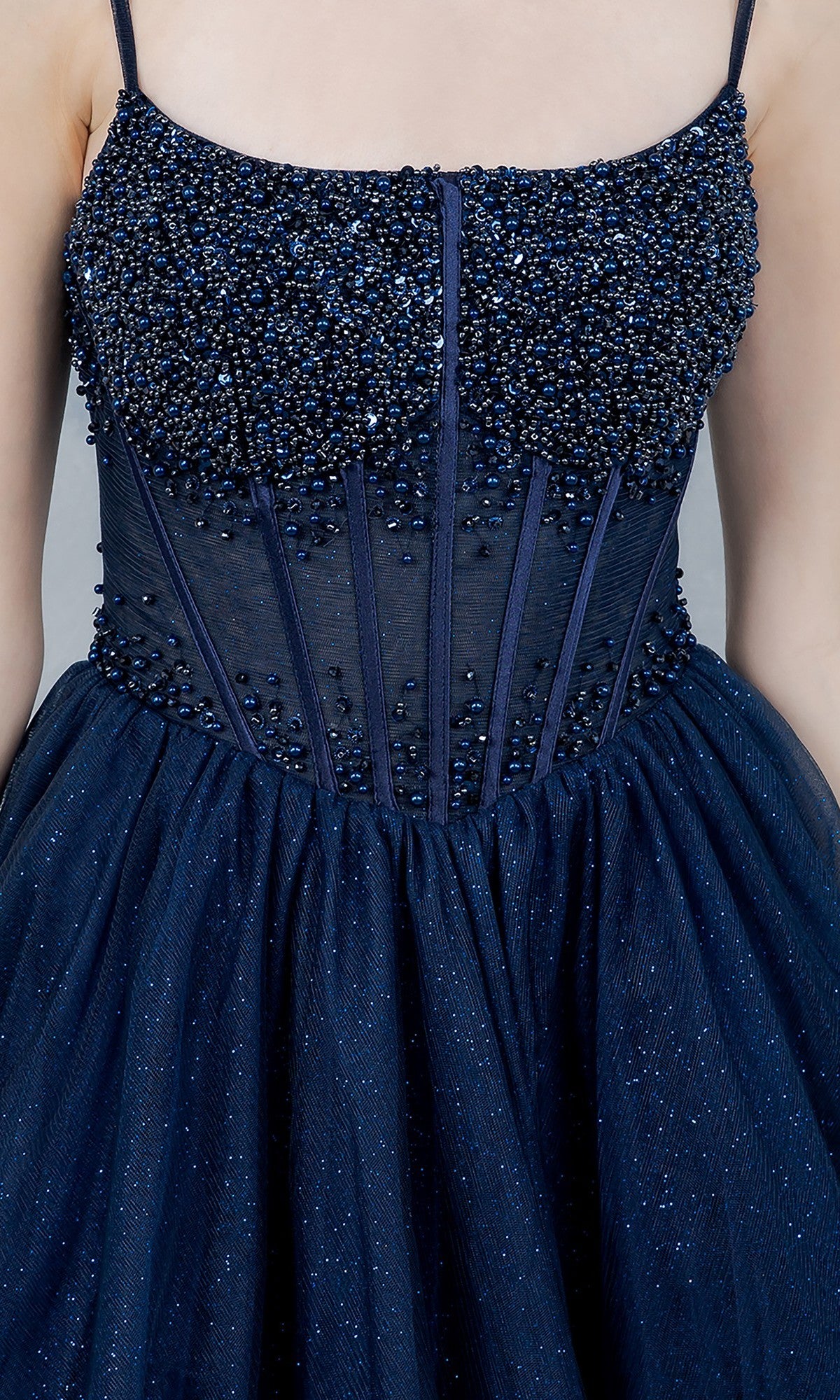 A close-up of a woman wearing the Cinderella Couture 8459J long prom dress, featuring a dark blue beaded corset bodice with thin straps, sheer detailing, and an elegant A-line tulle skirt.